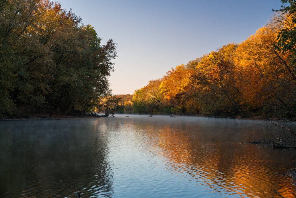View looking down the White River with colorful orange and yellow autumn trees along its banks.