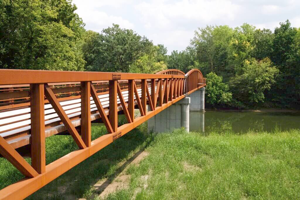 View of pedestrian bridge across White River with a forest in the background.