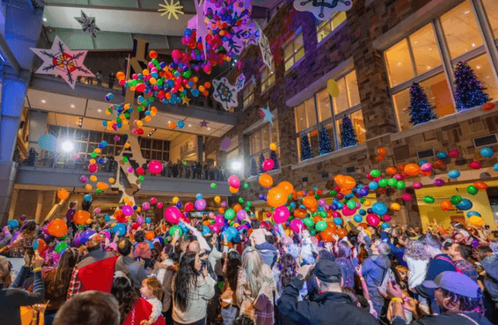 balloons being dropped from ceiling onto people standind