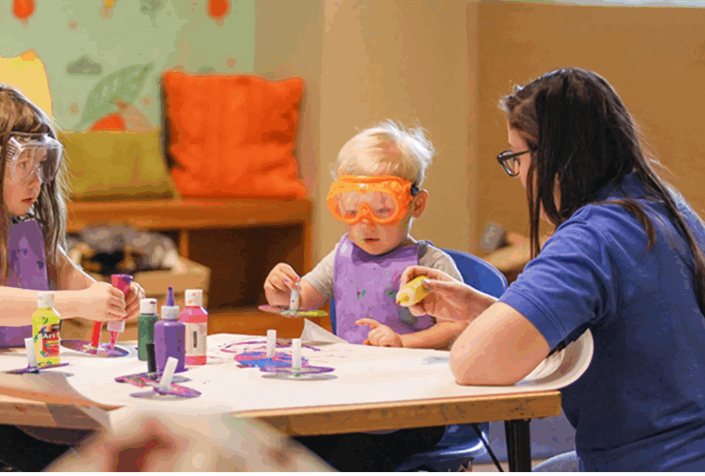 child with safety glasses at a table making a mess