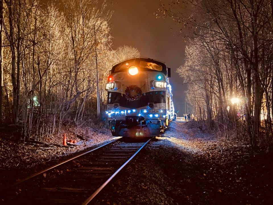 Holiday train with christmas wreath and lights in a winter scene.